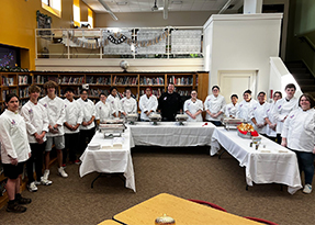 Student chefs in white around a buffet table