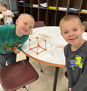Two young boys smiling from their desk