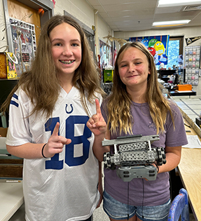 Two girls holding up a project in the classroom