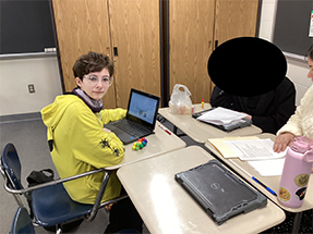 Boy in yellow sweatshirt working at a computer
