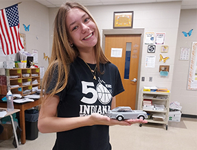 School girl smiling and holding a model car in her hand