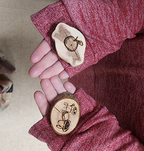 Student holding wood pieces with artwork