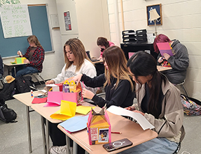 Three girls writing at their desk in the classroom