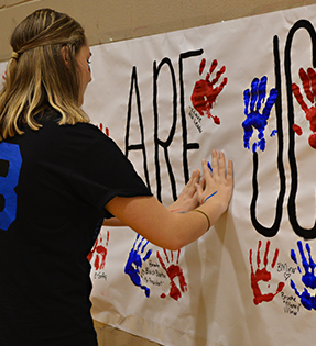 Student making paint handprint on banner