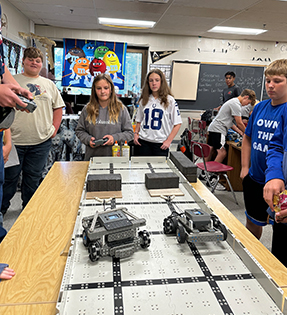 Students in the classroom having fun operating robots