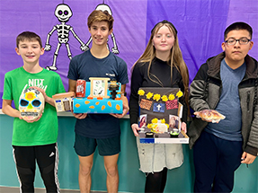 Four students holding up their art projects