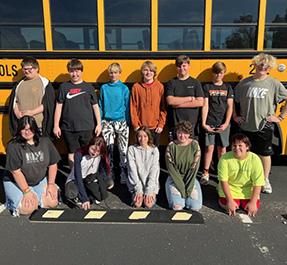 students lined up in front of a school bus 